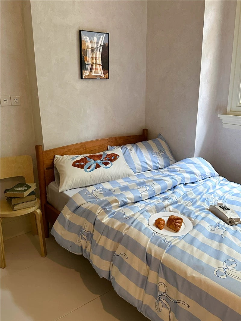 Bedroom with a bed featuring blue and white striped bedding, wooden headboard, and small table.