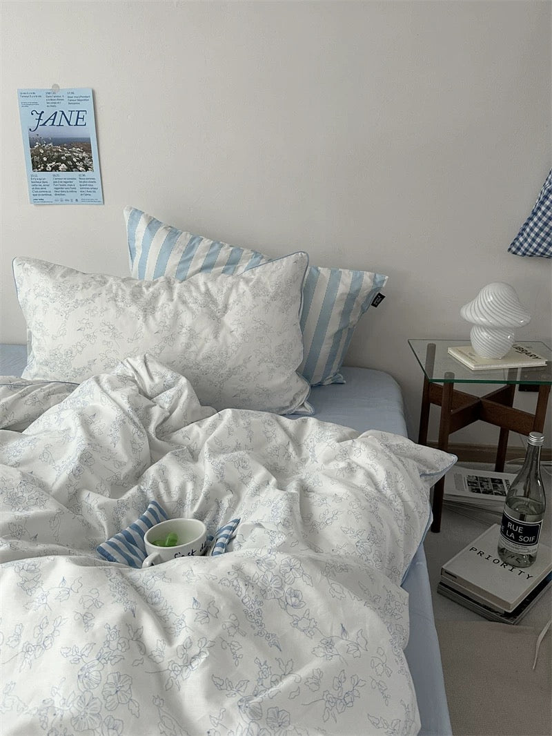 Bedroom with white bedding and striped pillows, nightstand with lamp and water bottle.