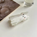 A group of colorful acetate cat hair claw clips in various cartoon designs resting on a beige ceramic plate
