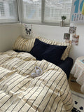 Bed with striped bedding and a black pillow in a room with a window and wall decorations.