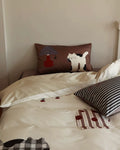 Bed with decorative pillows featuring animal designs on a neutral background