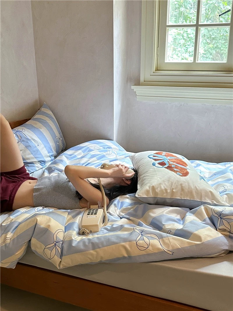 Person lying on a bed with patterned bedding and a phone beside them.