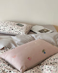 Neatly made bed with a pillow featuring cartoon designs on a polka dot blanket.