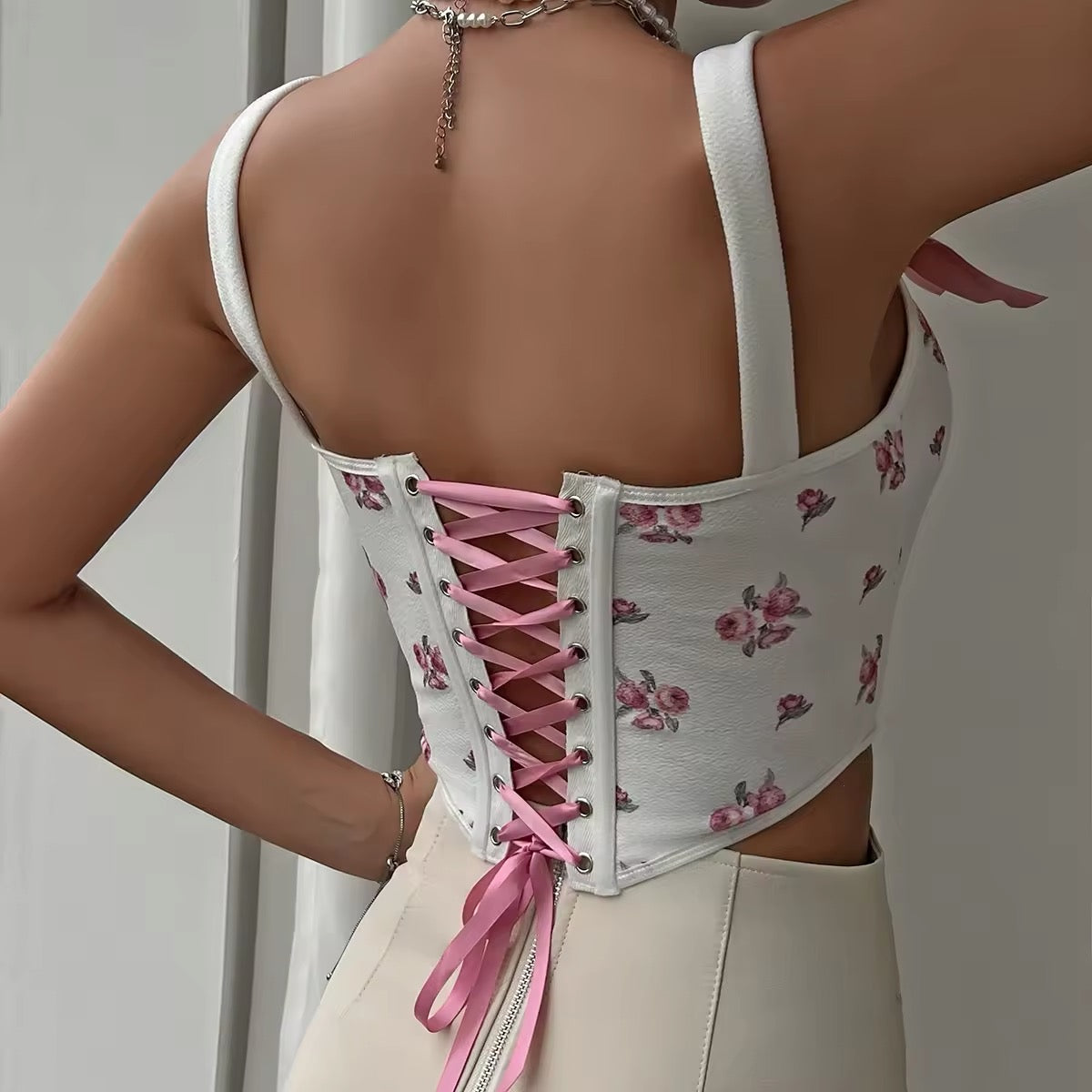 Y2K-inspired pink bustier corset with lace-up back and floral accents