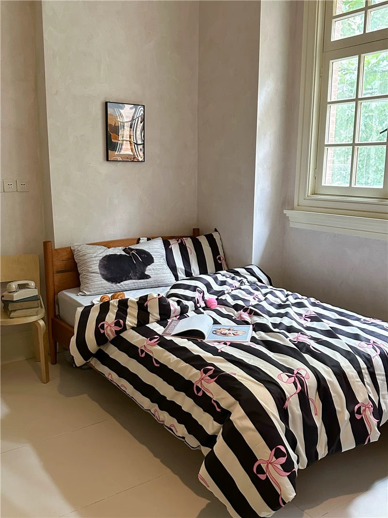 Bedroom with a bed featuring black and white striped bedding with pink accents.