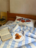 Bed with blue and white striped bedding, a plate of croissants, and an open book.