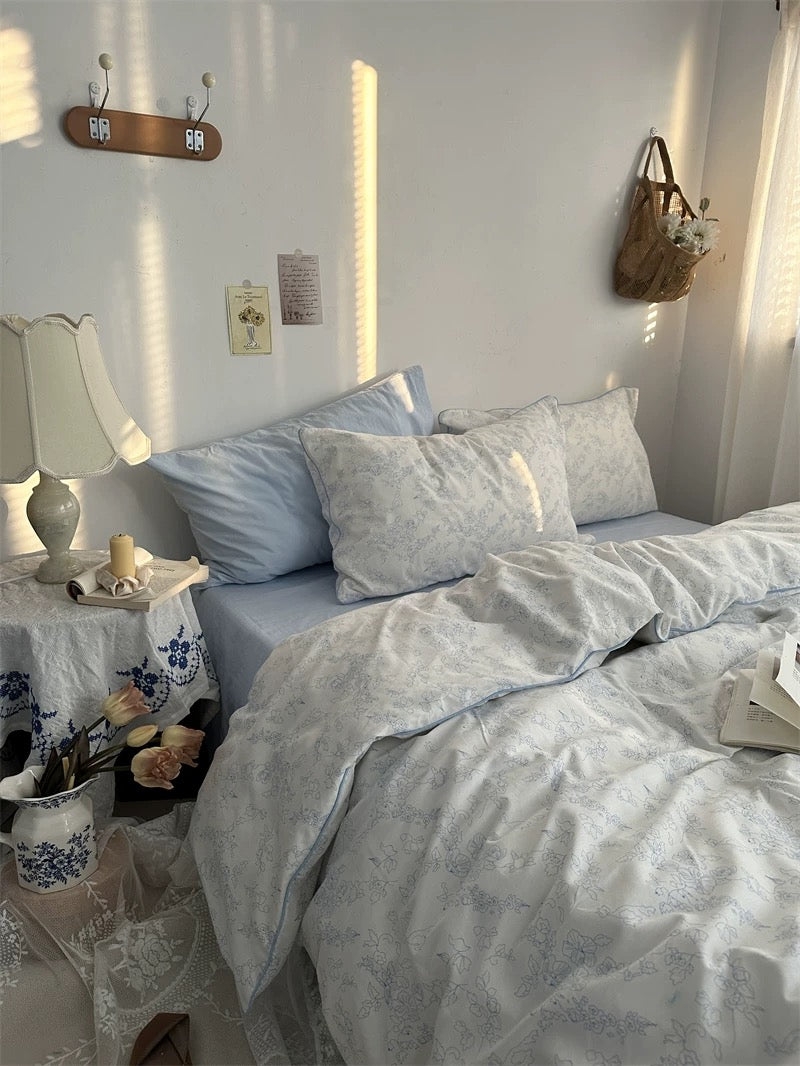 Neatly made bed with light blue bedding in a bedroom setting.