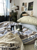 Room with a bed, tablet on striped blanket, and various decor items.