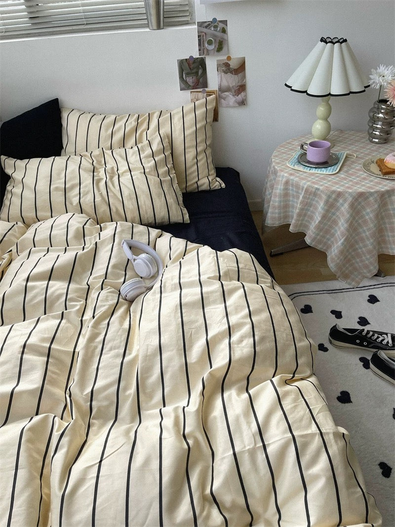 Bedroom with striped bedding and a nightstand with a lamp.