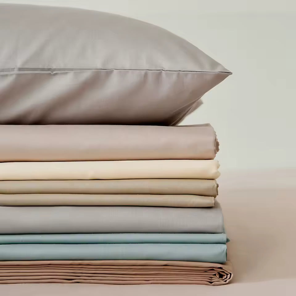 Stack of folded beige, gray, and brown fabrics on a wooden surface with a small jar.