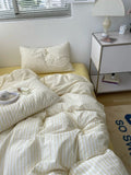 Bed with white striped bedding and a nightstand in a bedroom setting