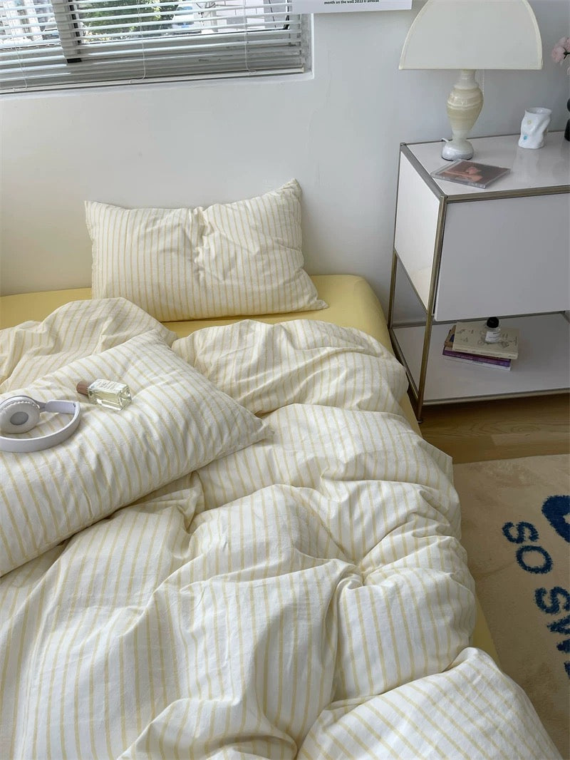 Bed with white striped bedding and a nightstand in a bedroom setting