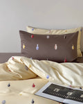 Bedding set with decorative elements on a bed with a tablet on top.