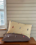 Two pillows with small decorative items on a wooden surface near a window.
