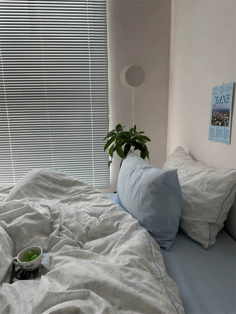 Bedroom with a bed, pillows, and a plant near a window with blinds.