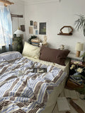 Bedroom with a bed, pillows, and a nightstand with books and a lamp.