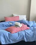Preppy blue bedding set with red checkered pillowcases styled on modern bed