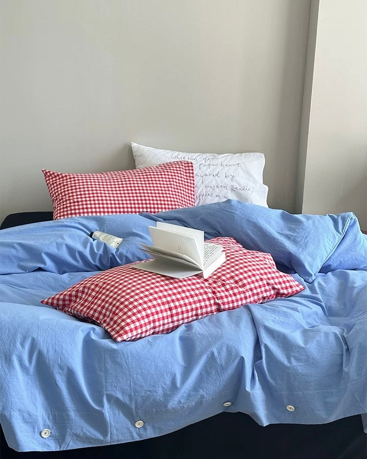 Preppy blue bedding set with red checkered pillowcases styled on modern bed