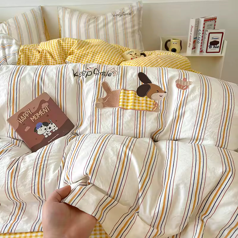 Striped bedding with cartoon dog design and a hand holding a pillow with a cow design.