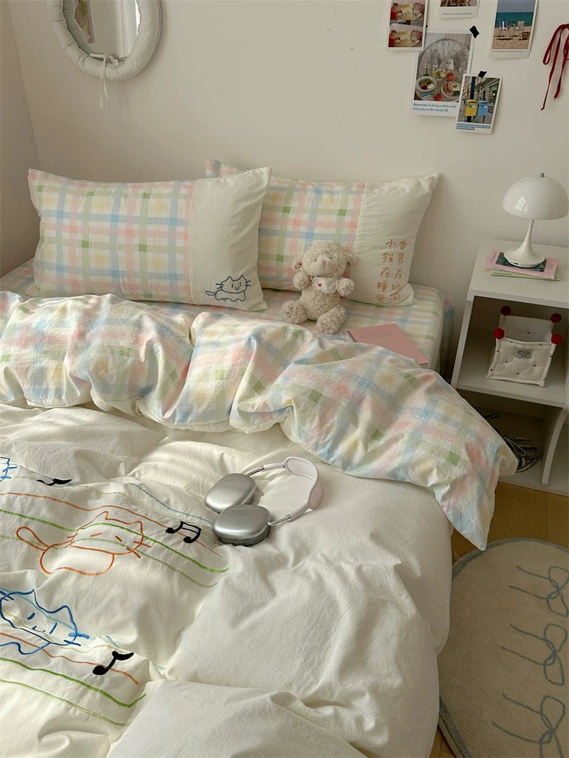 Bed with pastel checkered bedding and a teddy bear, nightstand with lamp and photos in the background.