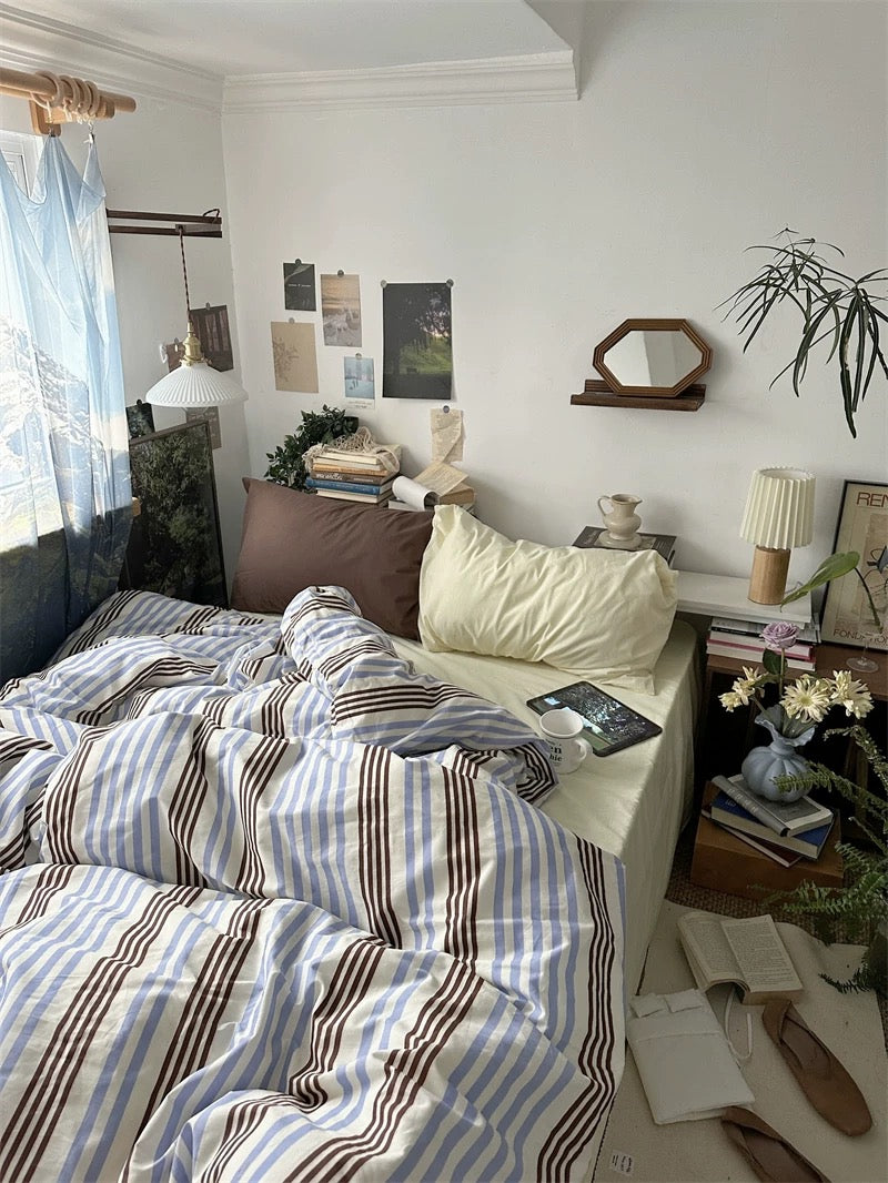 Cozy bedroom with striped bedding, laptop, and decor items.