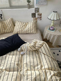 Bed with striped bedding and pillows in a bedroom setting.