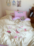 Bed with pink checkered pillow and cartoon-themed bedding in a room setting.