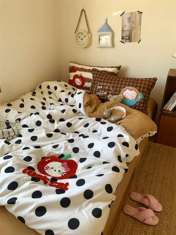 Bed with polka dot comforter and cartoon design, surrounded by decorative pillows and a clock on the wall.