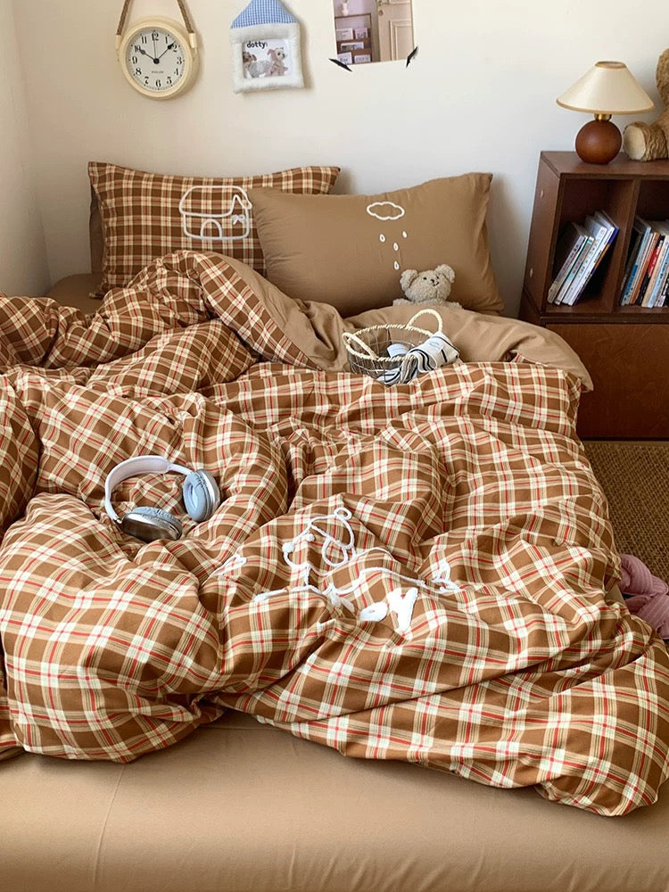 Bed with brown plaid bedding and pillows, teddy bear, and small clock on wall.