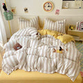Striped bedding with cartoon characters on a bed in a room with a clock and decor items.