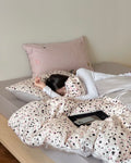 Person lying on a bed with polka dot comforter and pillows