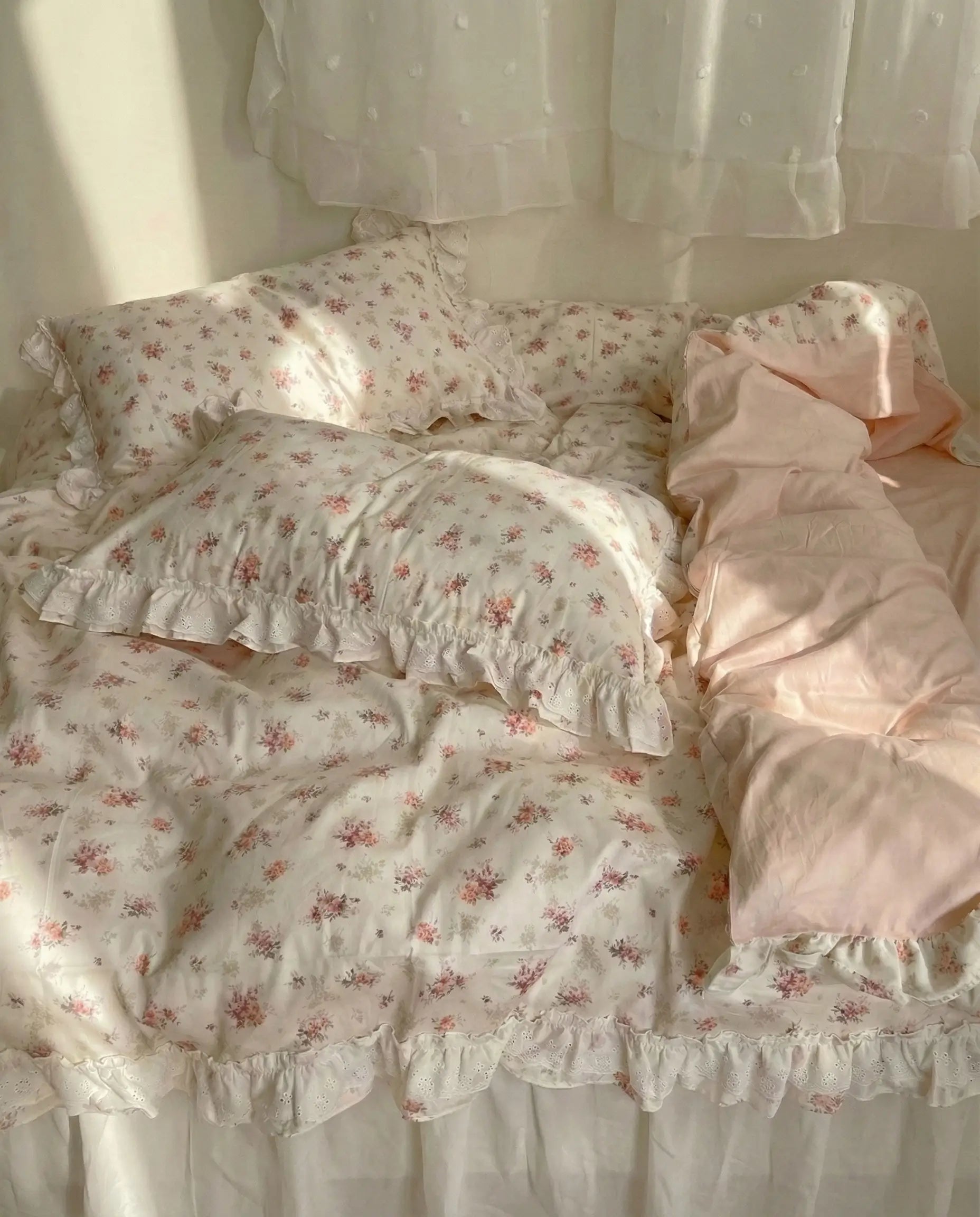 Floral bedding set with ruffled edges on a bed.