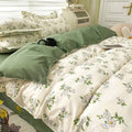 Floral bedding set on a bed with a green throw blanket.