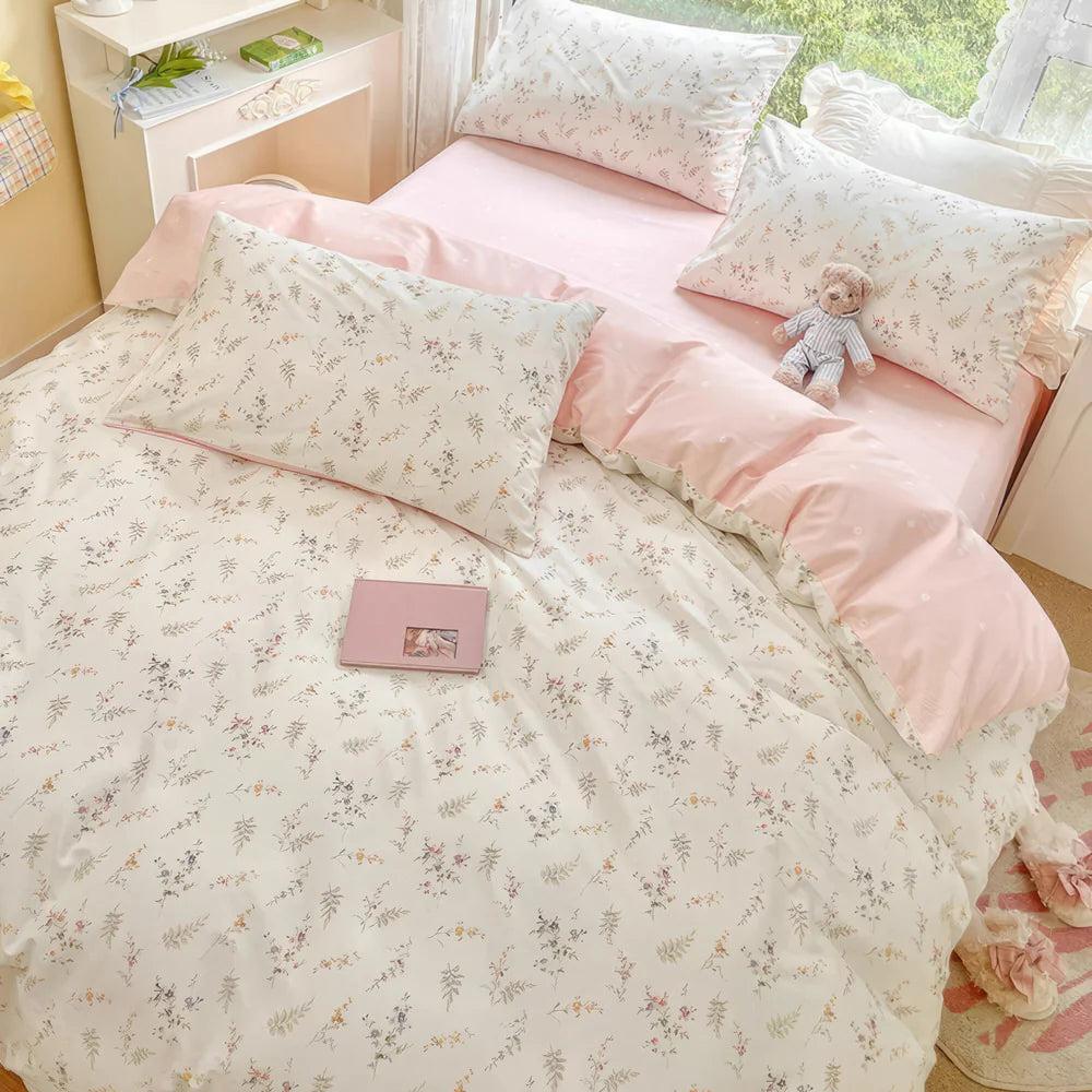 Floral bedspread on a bed with a teddy bear and small box in a bedroom setting.