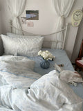 Bedroom with white bedding, pillows, and a vase of flowers on a bed.