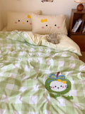 Bed with green and white checkered comforter featuring a cartoon character, next to a wooden nightstand.