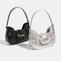 Underarm and crossbody style pink crescent handbag in faux leather with heart detail and silver rivets for gothic Y2K looks