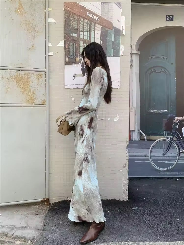 Model wearing tie dye maxi dress near a rustic backdrop, old money style