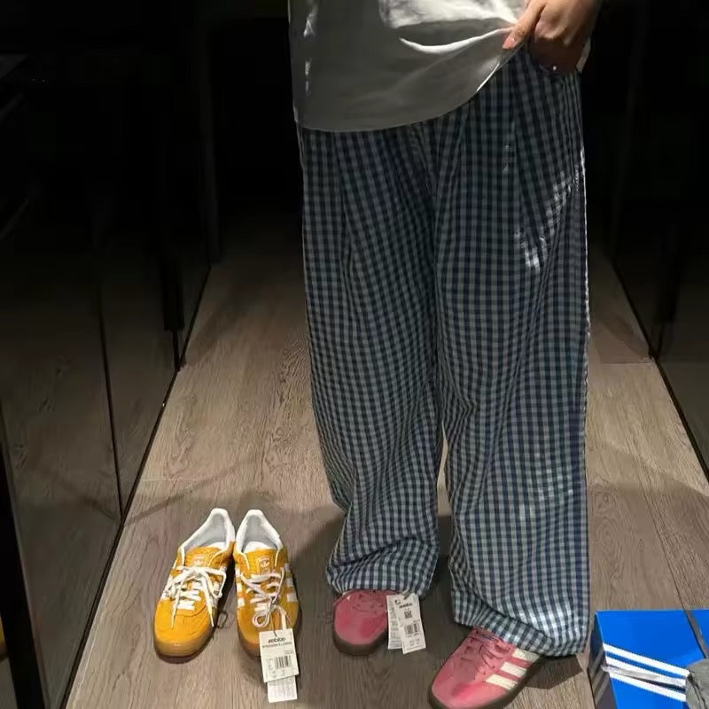 Woman wearing oversized plaid pants with elastic waistband, styled with yellow sneakers and a white tee