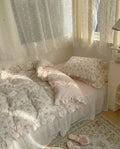 Floral bedding set on a bed with matching pillows and curtains in a softly lit room.
