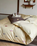 Beige bedspread with colorful patterns on a bed in a room setting.