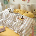 Striped bedding with cartoon characters on a bed in a room with yellow checkered pillows and a colorful rug.