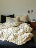Striped bedding on a bed with a nightstand in the background
