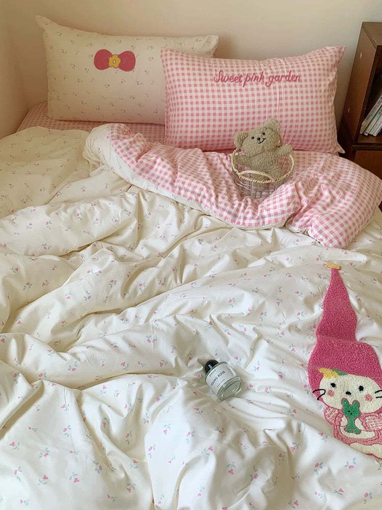 Bed with pink and white checkered blanket, teddy bear, and cartoon character pillow