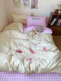 Bed with pink checkered bedspread and decorative pillows in a bedroom setting.