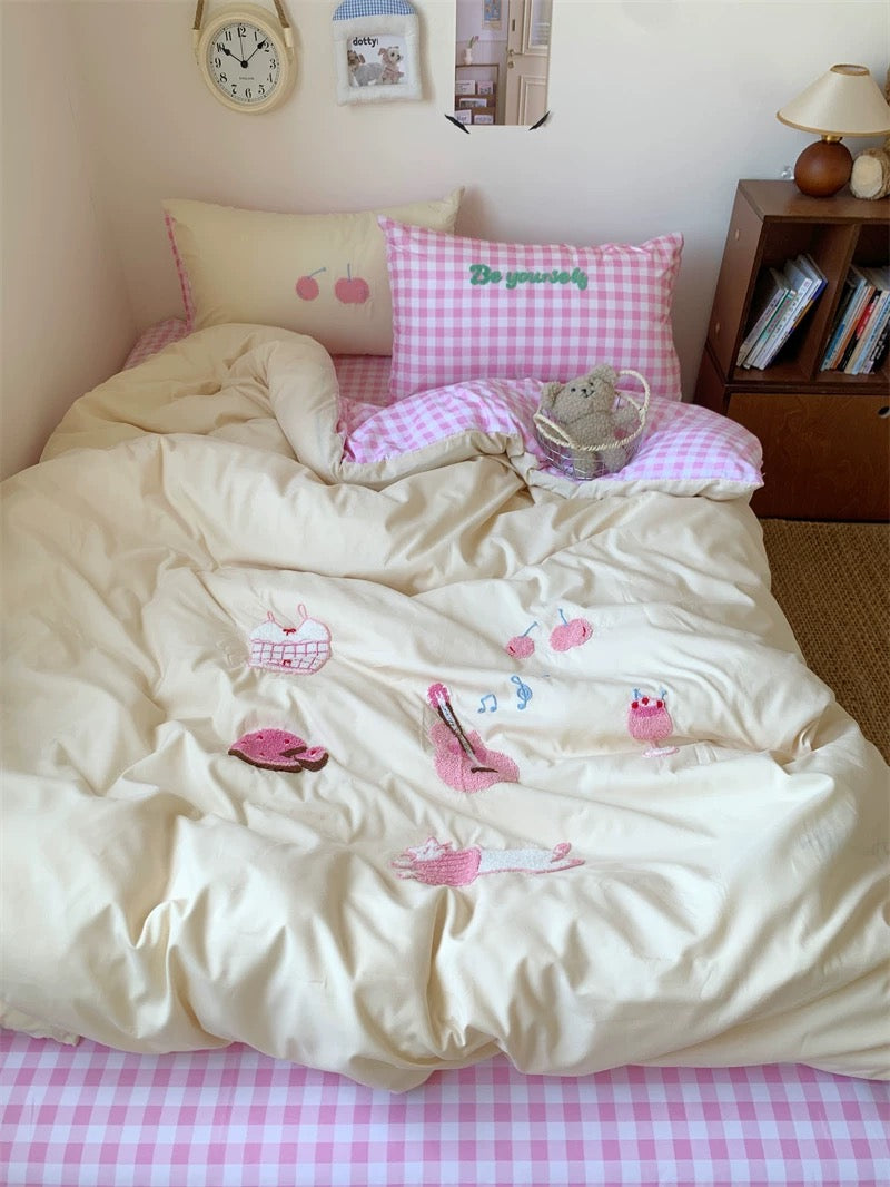 Bed with pink checkered bedspread and decorative pillows in a bedroom setting.