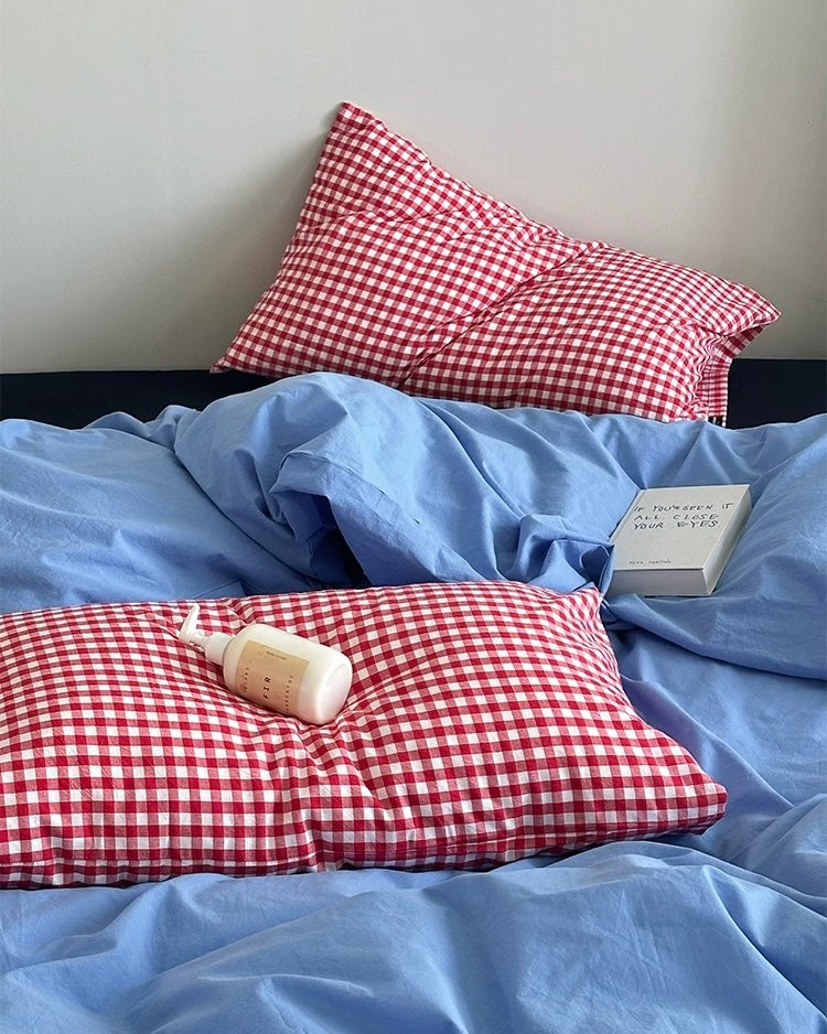 College bedroom bed featuring blue cotton duvet and red plaid pillowcases