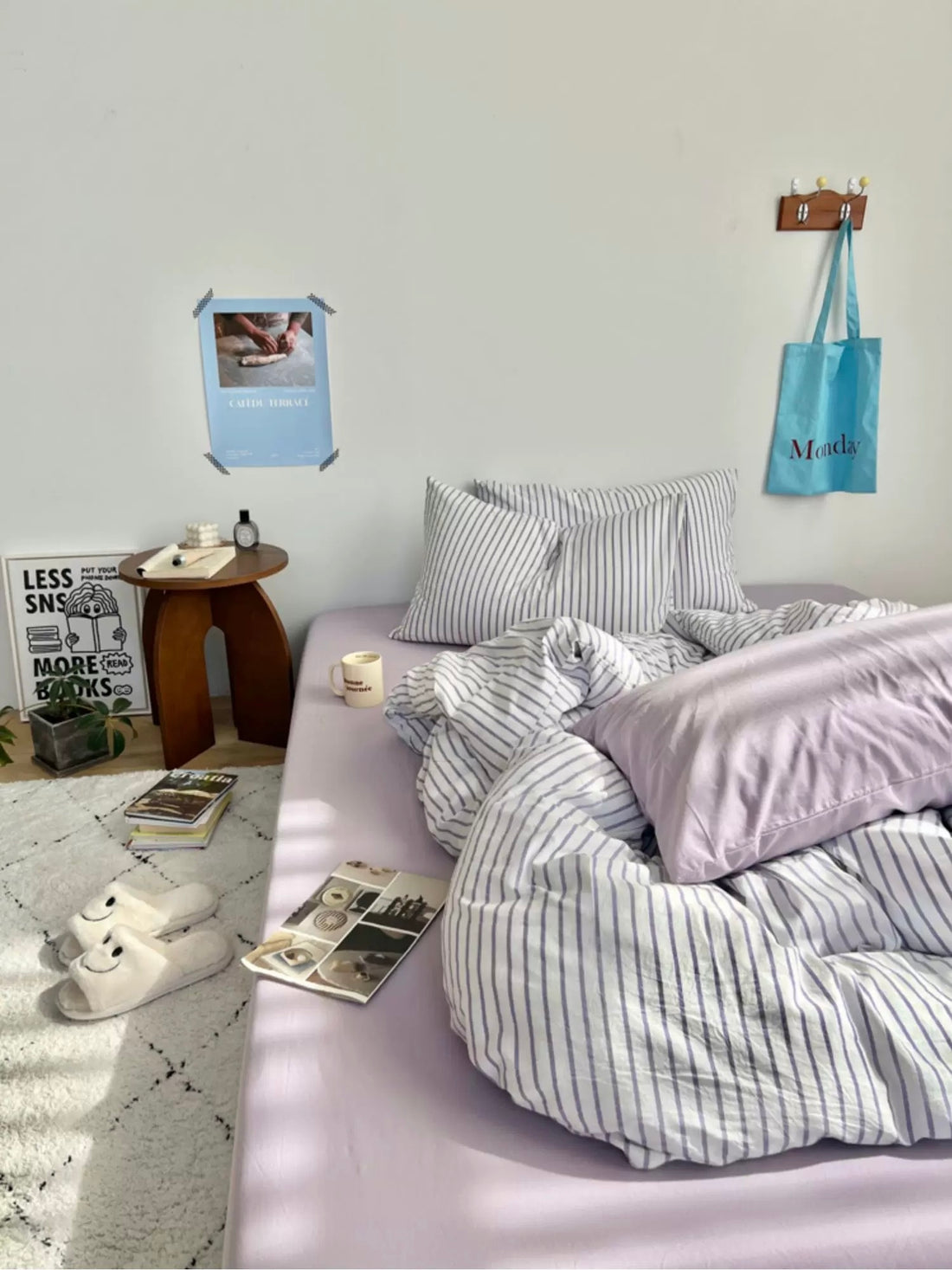 Bedroom with striped bedding and pillows on a bed, side table, and lamp.