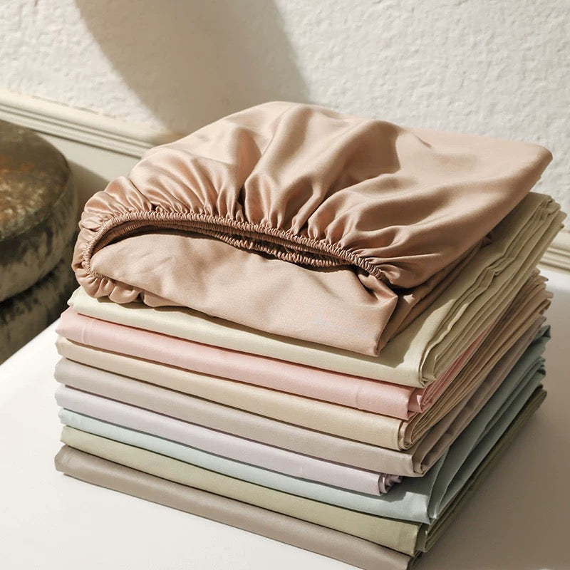Stack of folded pastel-colored bed sheets on a white surface.