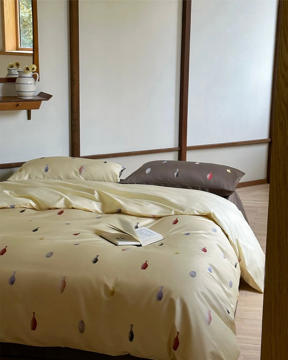 Beige bedspread with colorful leaf pattern on a bed in a bedroom setting.